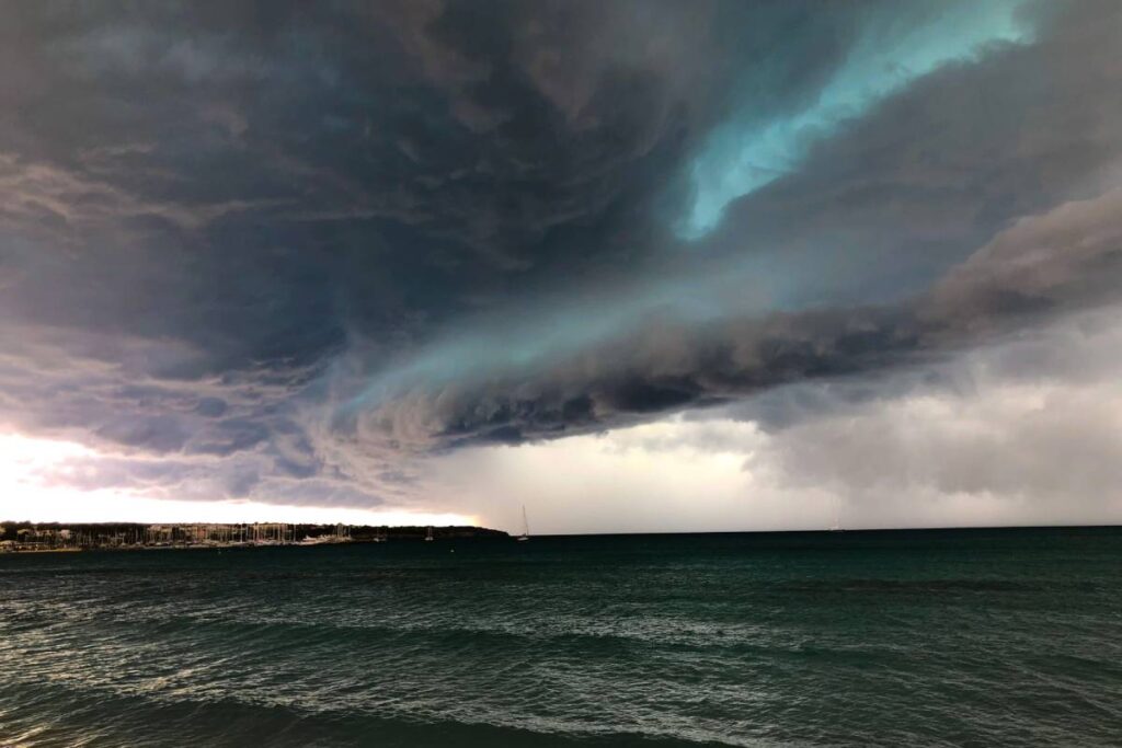 A powerful storm brewing over a serene ocean, with huge waves crashing onto the shoreline