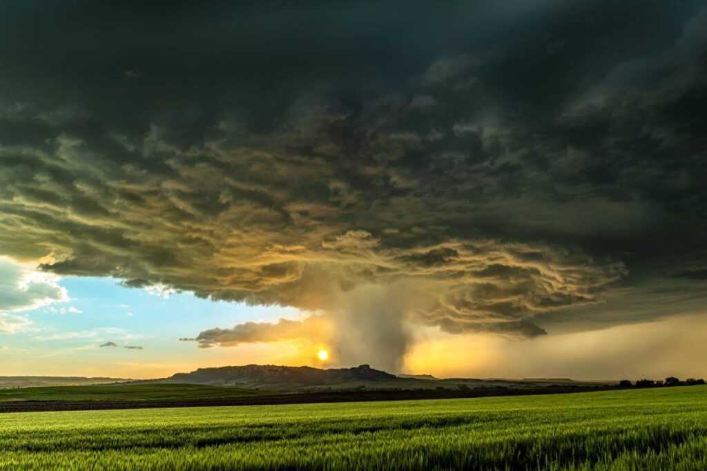 Panorama of a massive mesocyclone weather supercell, which is a pre-tornado stage, passes over a grassy part of the Great Plains while fiercely trying to form a tornado.