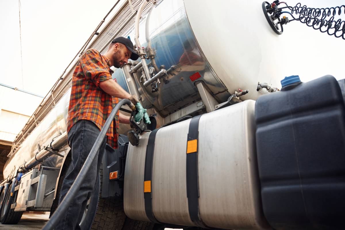 Young truck driver in casual clothes is refueling the vehicle.