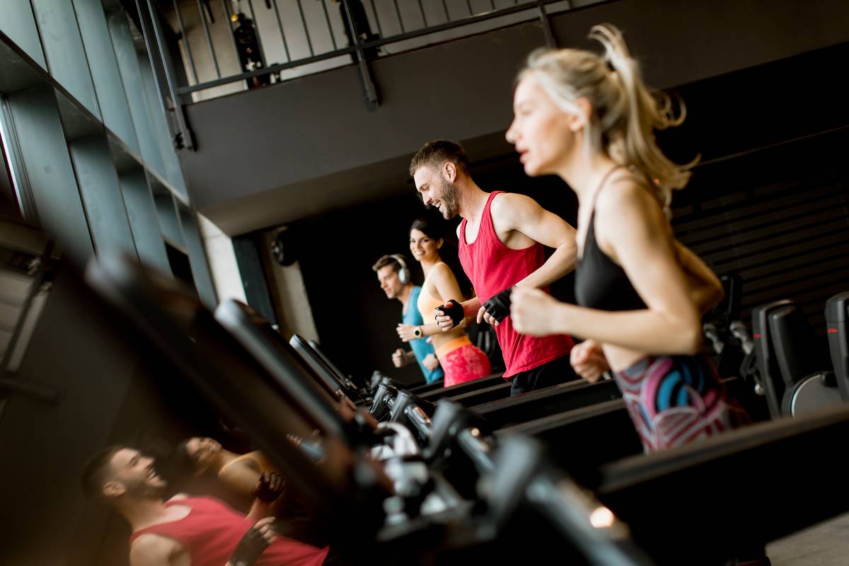 Group of young people running on treadmills in modern gym