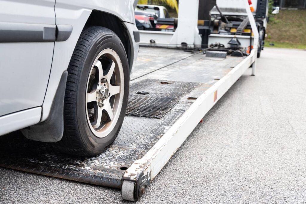 Cable attached to broken down car being pulled onto tow truck
