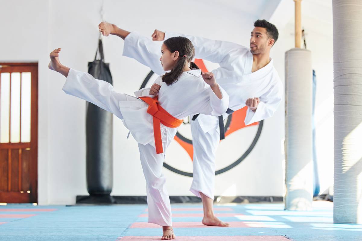 Shot of a young man and cute little girl practicing karate in a studio.