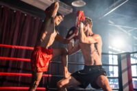Two young professional boxer having a competition tournament on stage. Attractive male athlete fighters muscular shirtless punches and hitting competitor enjoy boxing exercise in the ring at stadium.
